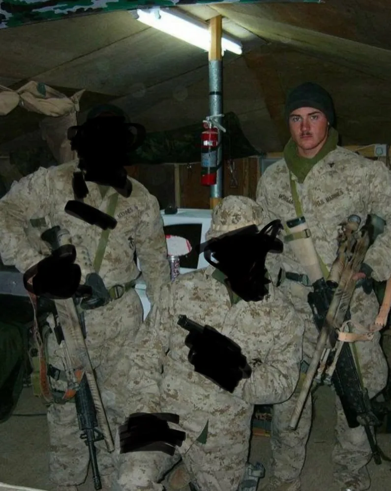 Three Marines in desert camouflage with sniper rifles inside a tent, other faces blacked out