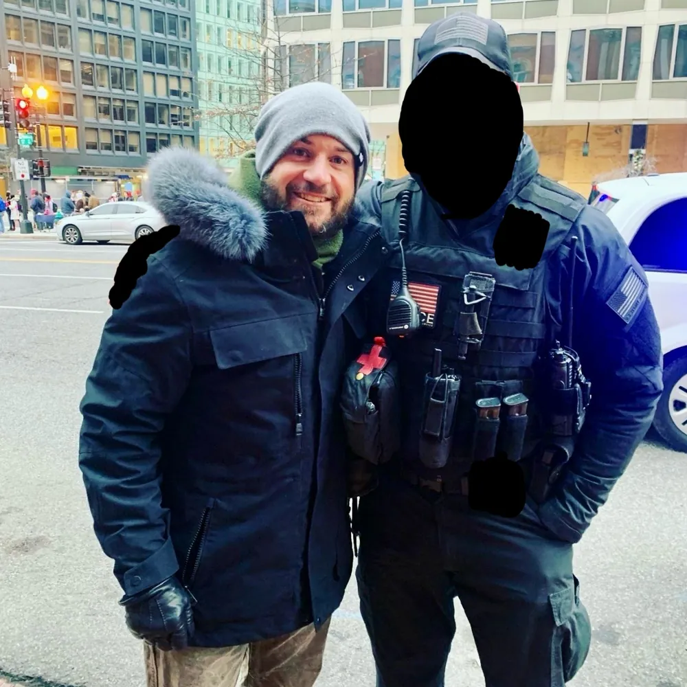 Sonny on a city street beside a uniformed officer whose face is blacked out